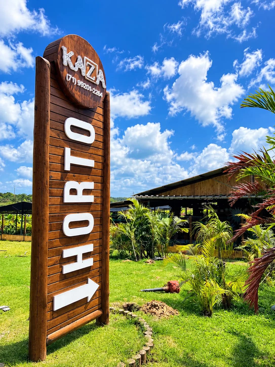 Placa de entrada do Horto Kazza em meio ao paisagismo tropical